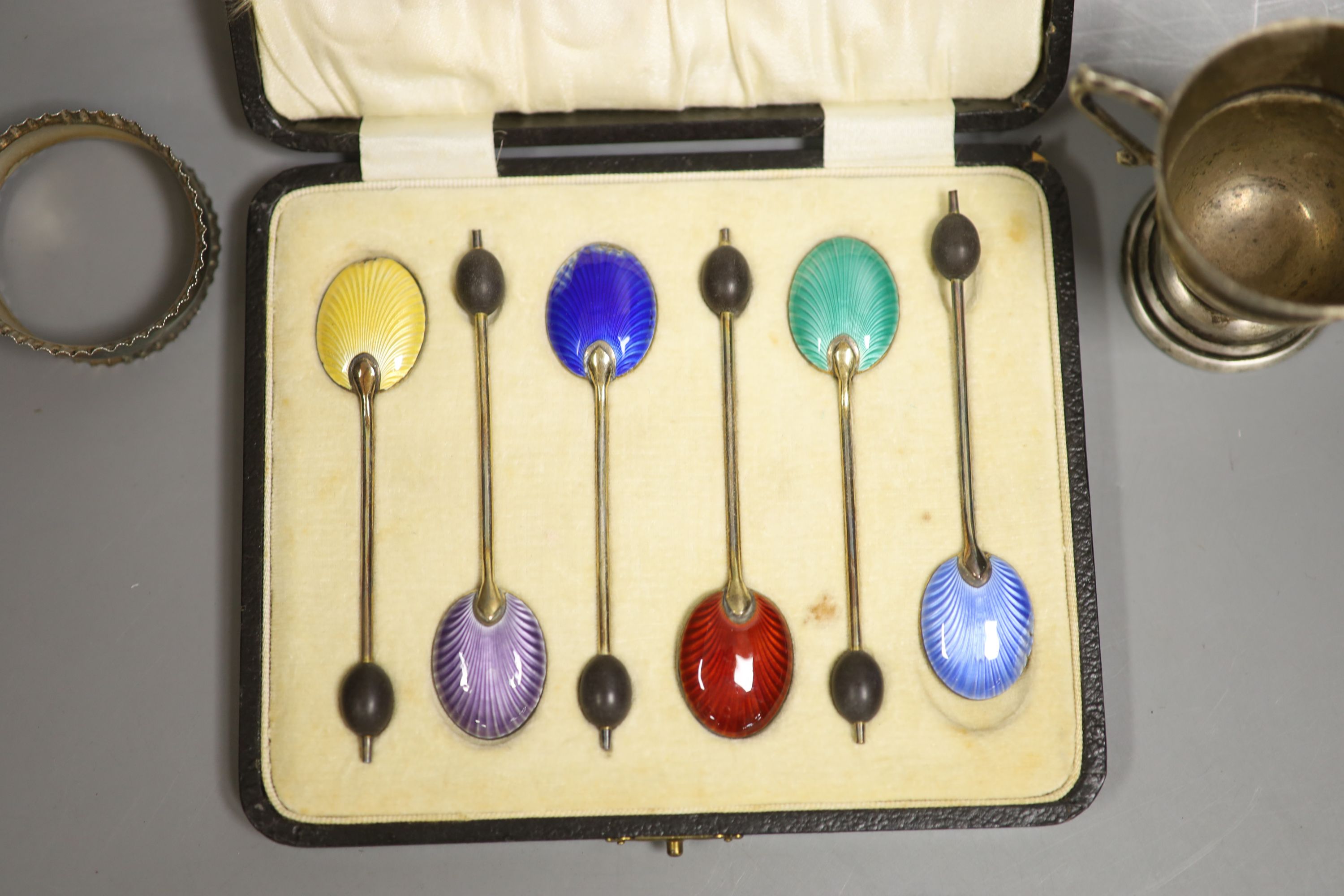 A cased set of six silver and enamel(a.f.) bean end coffee spoons, one other silver spoon, a silver napkin ring and small silver trophy cup.